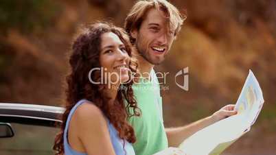 Smiling couple standing next to their car