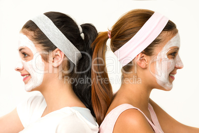 Girls sitting back-to-back wearing facial mask