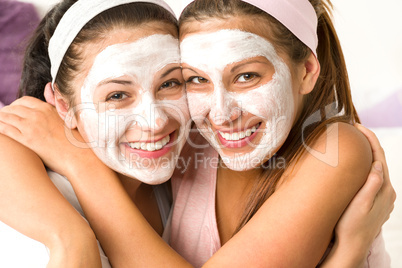 Blissful girls applying mask hugging each other