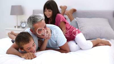 Father and his children playing on the bed