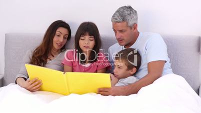 Family reading a story in bed