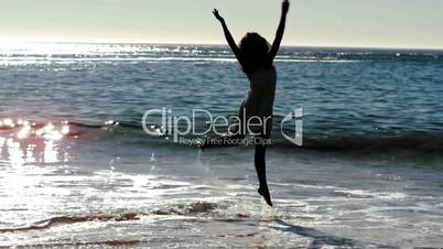 Silhouette of woman jumping on the beach
