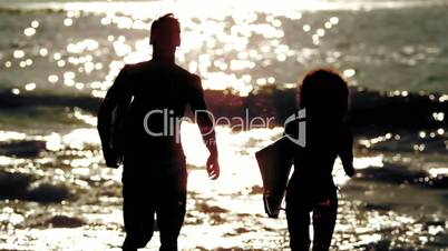 Friends with surfboard running on the beach