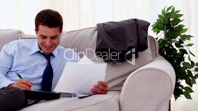 Smiling businessman sitting and working on a sofa