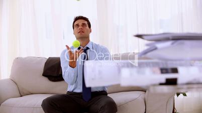 Happy businessman juggling with tennis ball