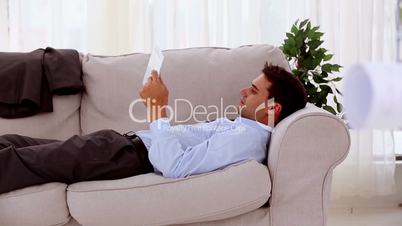 Tired businessman using his tablet on a couch
