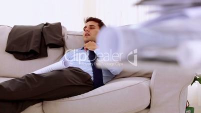 Businessman lying on couch and looking at a document