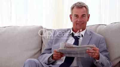 Smiling businessman reading newspapers