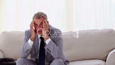 Businessman sitting on couch and opening an umbrella