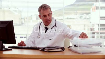 Doctor searching document and using his computer