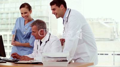 Smiling doctor showing something to his colleagues on his computer