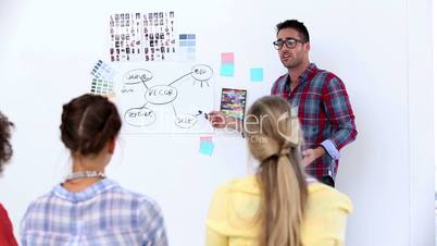 Handsome designer pointing at a plan on a wall