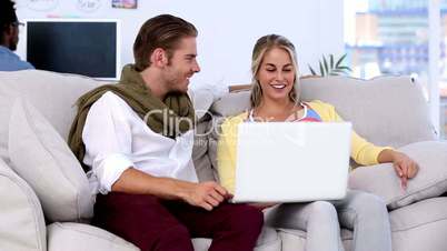 Colleagues sitting on couch working on a laptop