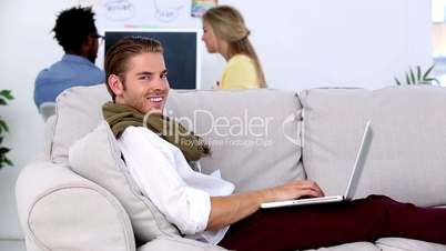 Man working on laptop on the couch and smiling