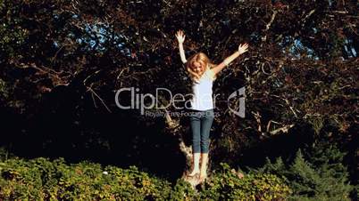Cheerful blonde little girl jumping on a trampoline