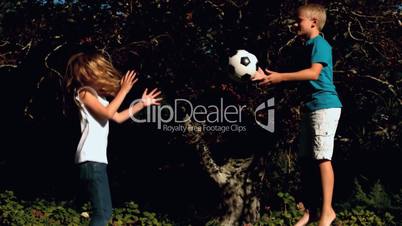 Cheerful siblings having fun with a football on a trampoline