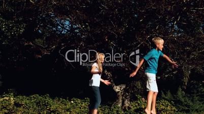 Siblings jumping on a trampoline