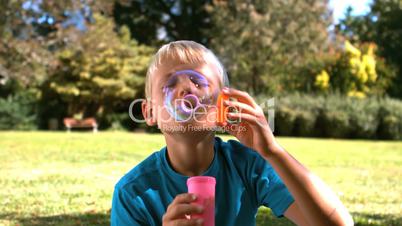 Cheerful young boy blowing into a bubble wand