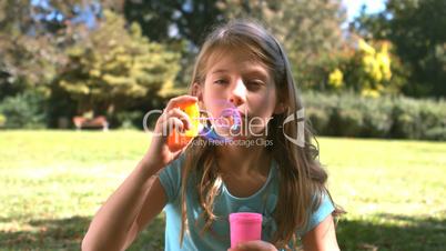 Cute young girl blowing into a bubble wand