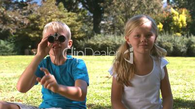 Brother with binoculars showing something to his sister
