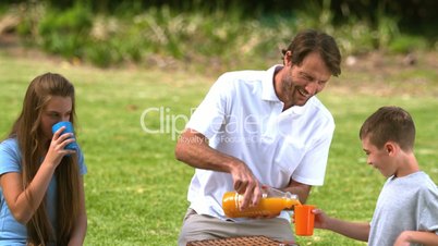 Father pouring orange juice into a plastic glass