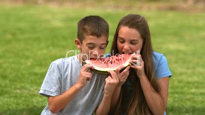 Siblings eating watermelon together