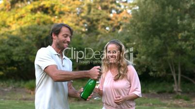 Happy man shaking a bottle of champagne and kissing his wife