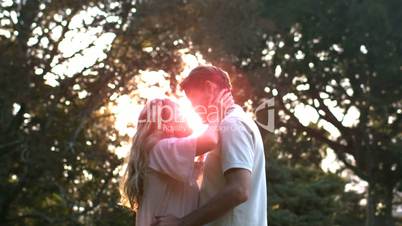 Delighted couple kissing in front of the sunset