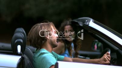 Man closing up his car door while his girlfriend look at him