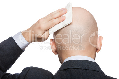 hand holding tissue wiping or drying bald sweat head