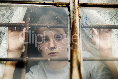 The boy looks out of the window through a lattice