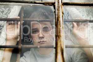 The boy looks out of the window through a lattice