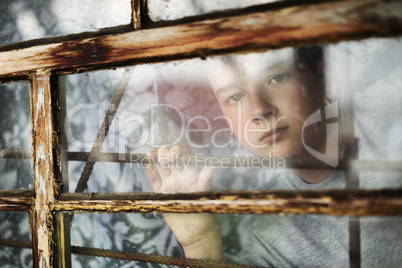 The boy looks out of the window through a lattice