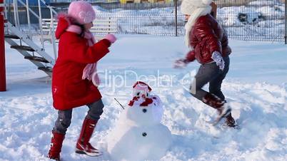 Happy girls running around a snowman
