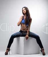 Attractive woman posing on cube in studio