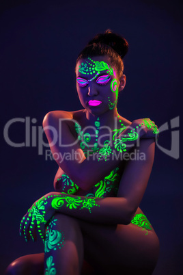 Naked woman posing with colorful UV makeup