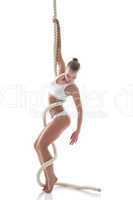 Pretty slim gymnast posing on rope in studio
