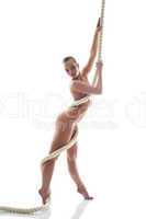 Slim nude woman posing holding rope in studio