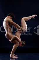 Young naked gymnasts showing trick in studio