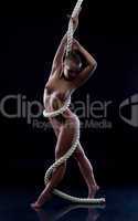Slim nude girl posing with rope on blue backdrop