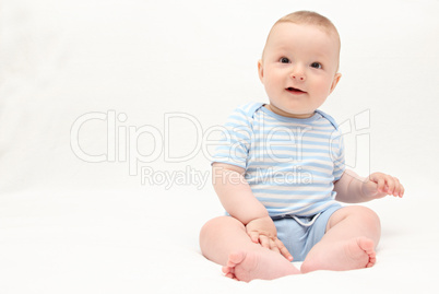 beautiful laughing happy baby boy sitting on white bed