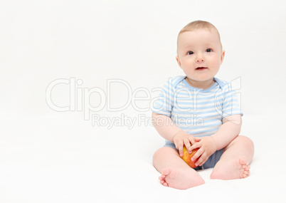 beautiful happy baby boy sitting on white bed with apple