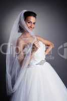 Portrait of smiling bride hiding behind veil