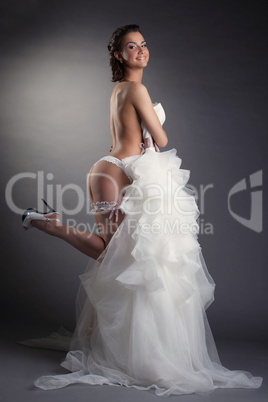 Young cheerful bride posing in white lingerie