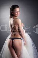 Smiling topless bride posing back to camera