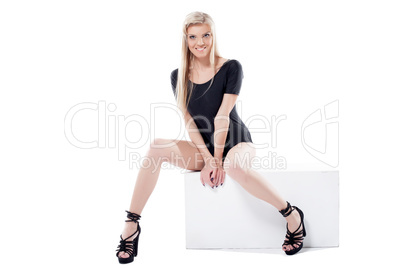 Cheerful leggy blonde posing on cube