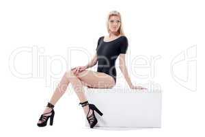 Seductive slim model posing sitting on cube
