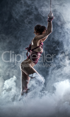 Flexible naked girl posing on smoke backdrop