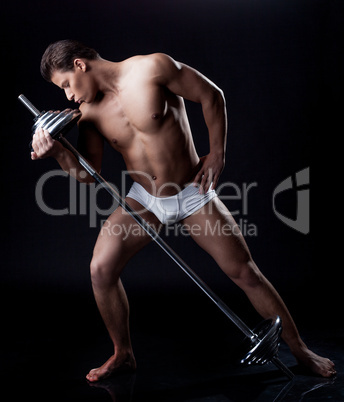 Brawny young man posing kissing barbell