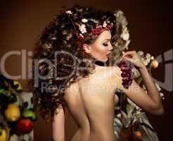 Curly topless brunette posing with grape